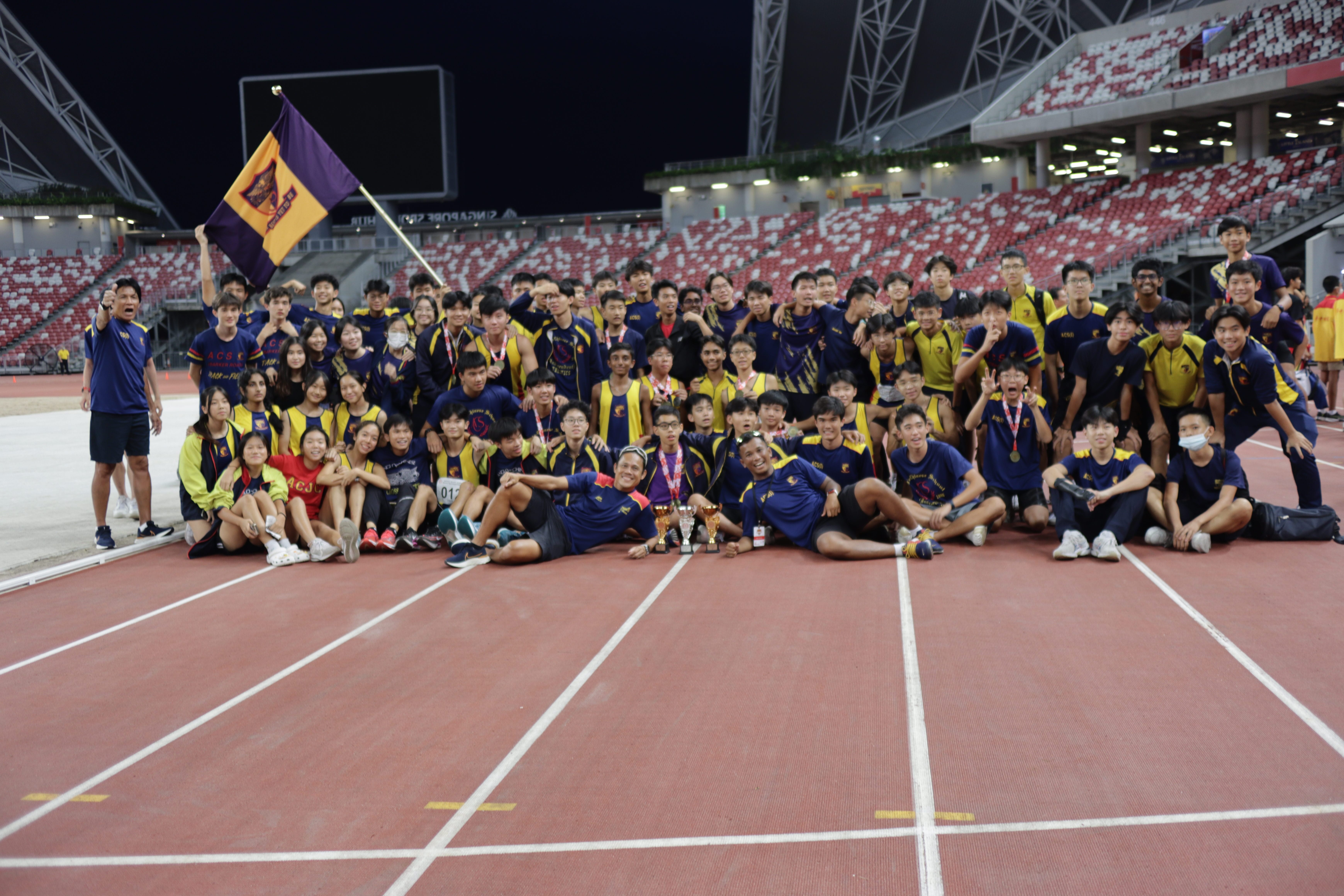 A large group of students posing on the track at the National Stadium